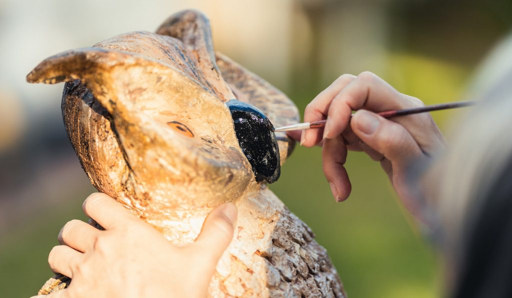 Woman painting a polystyrene owl figurine
