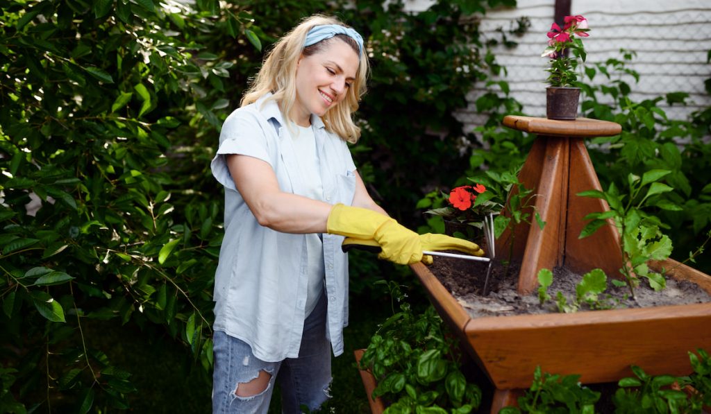 Woman with hoe at the flowerbed in the garden
