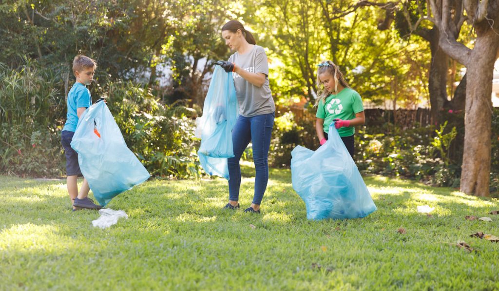 mother and kids cleaning garden putting garbage in sacks
