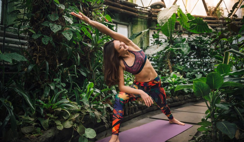  woman doing yoga exercises at the greenhouse